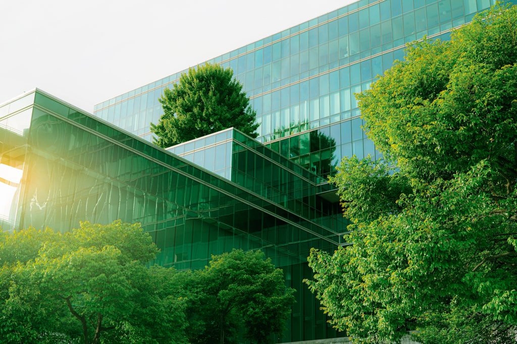 glass building highlighted in green surrounded green trees