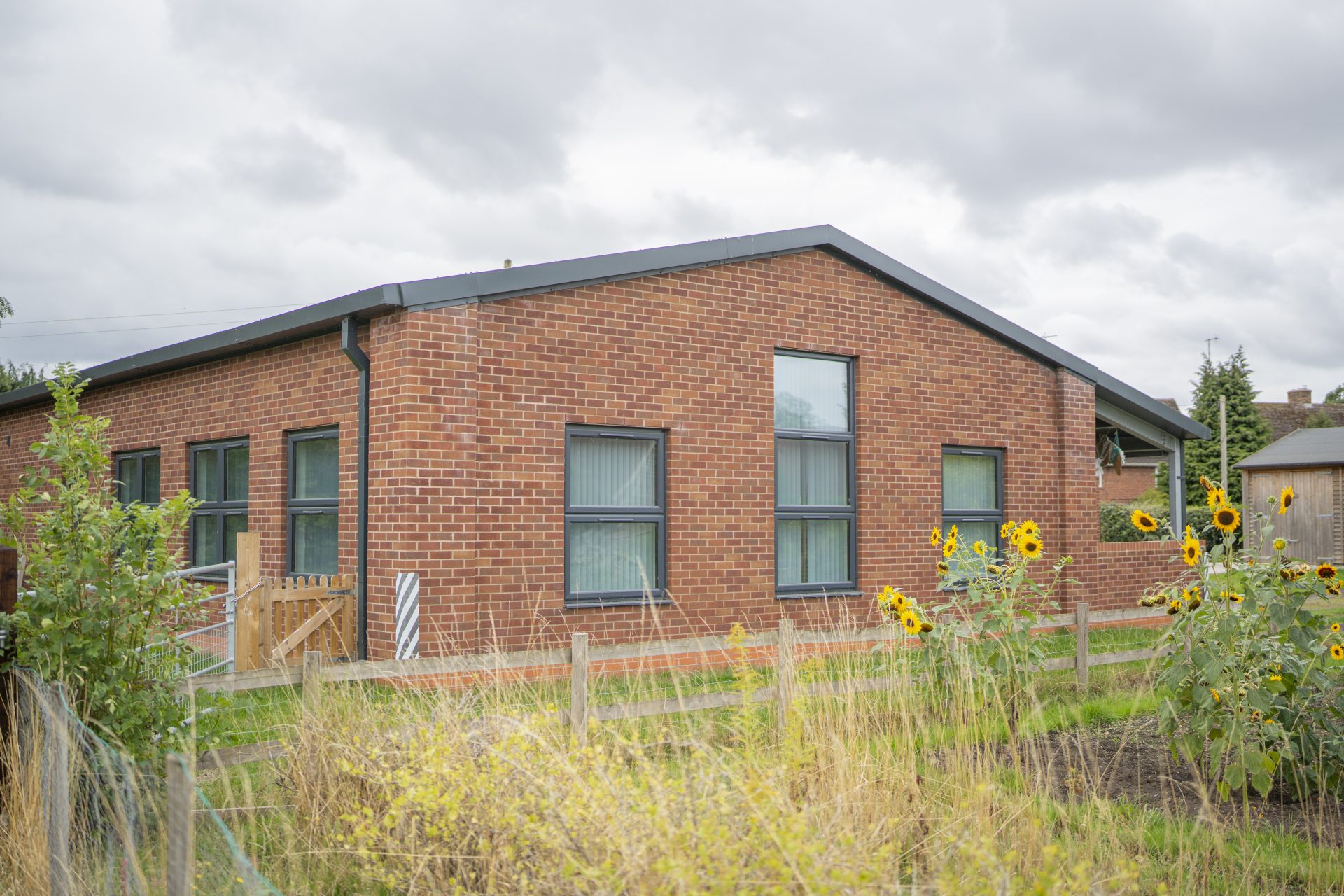 The back of Barford Youth & Community Centre, showing the next-door allotment and sunflowers.